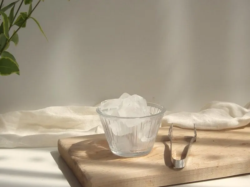 A bowl of ice cubes on a wooden board