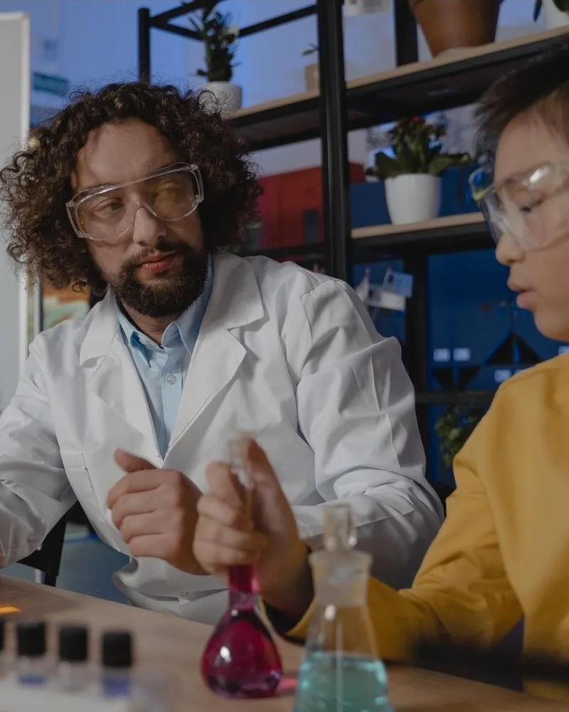 The teacher explains while a student holds up his flask, unconvinced